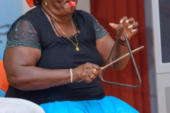 A performer playing the triang and whistle